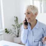 Senior woman using her phone. Happy woman relaxing at home, she is talking on her smartphone